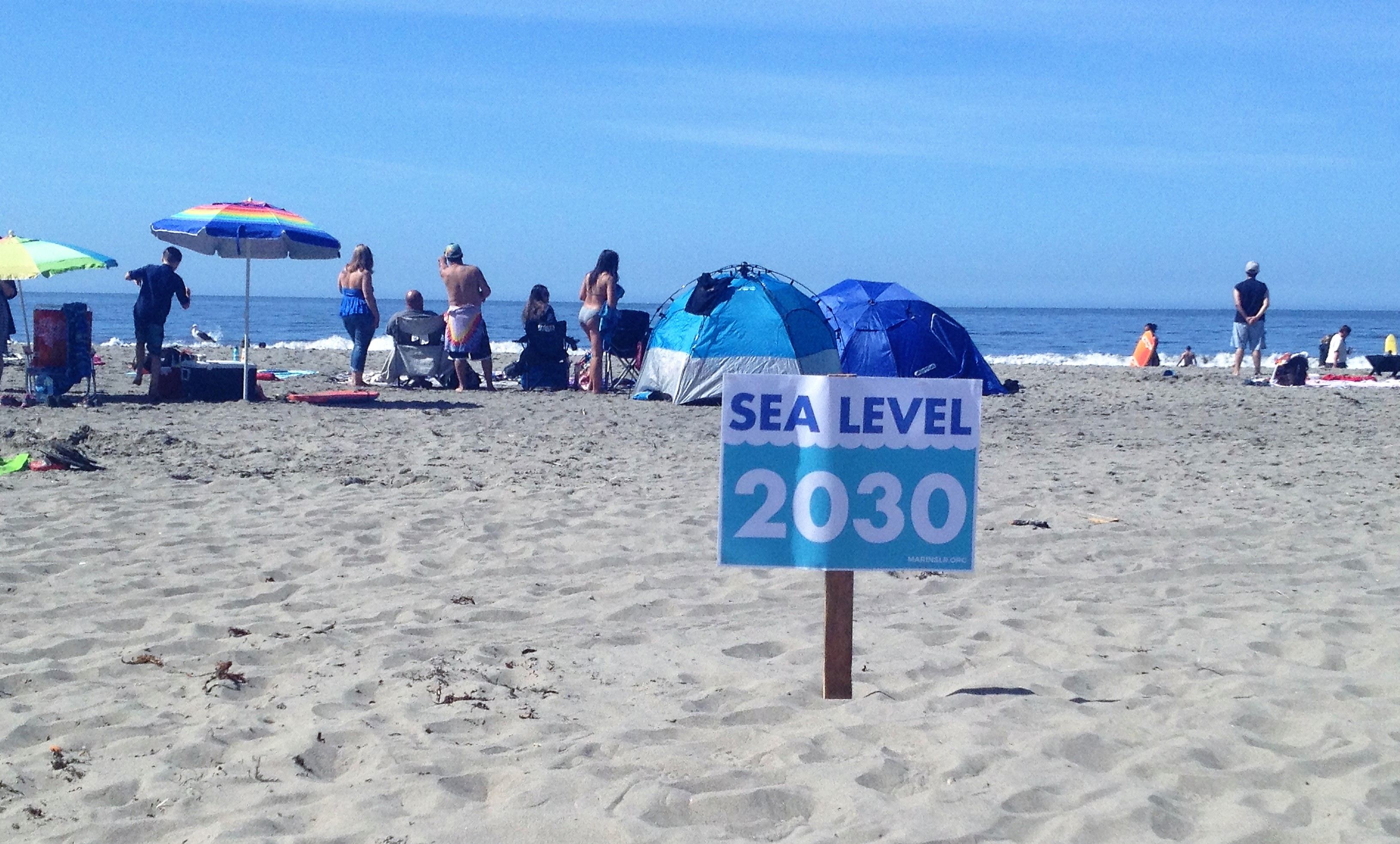 A sign in the sand at Stinson Beach says "Sea Level, 2030" as a reminder about climate change.