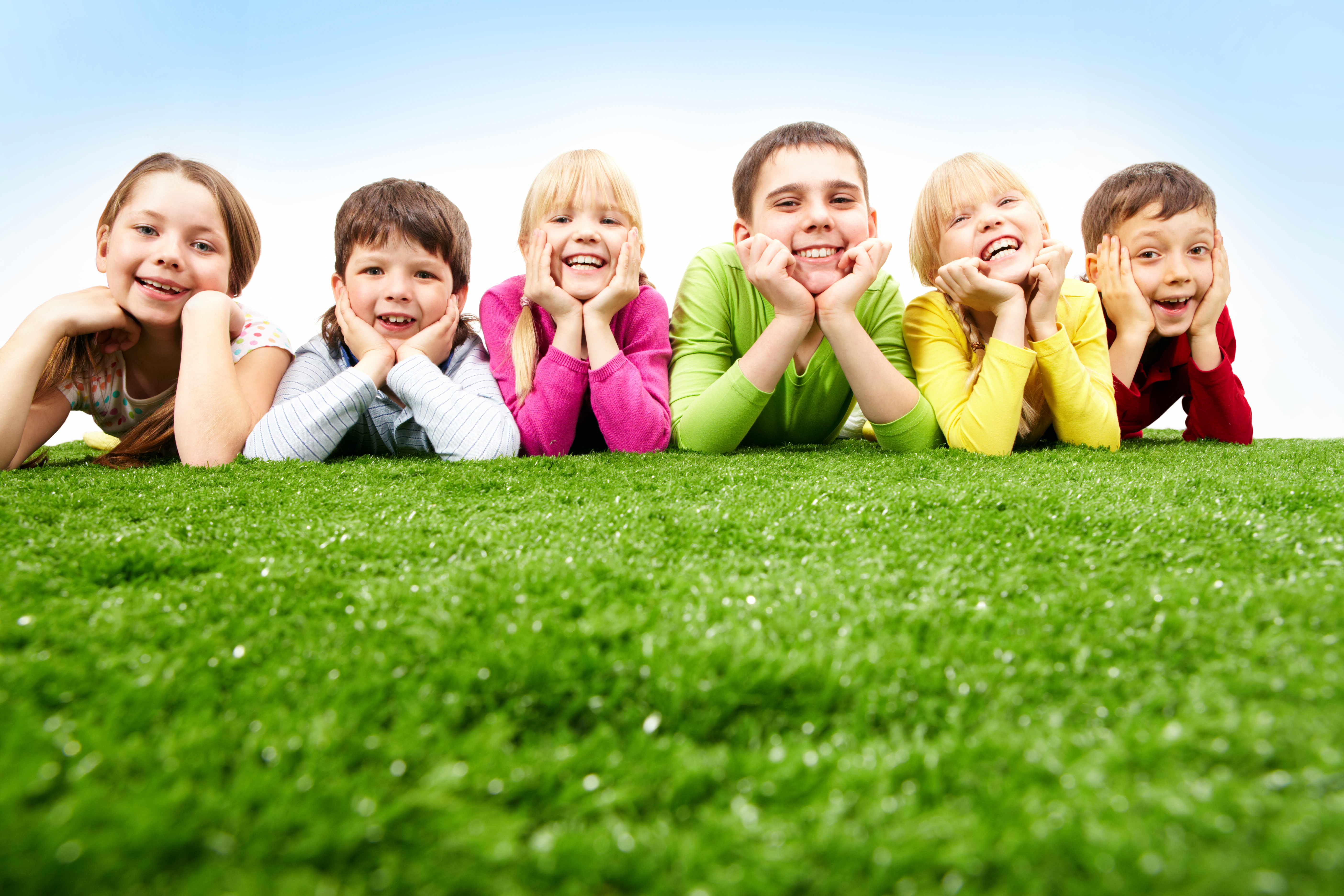 Six happy children smile together why lying down on the grass.
